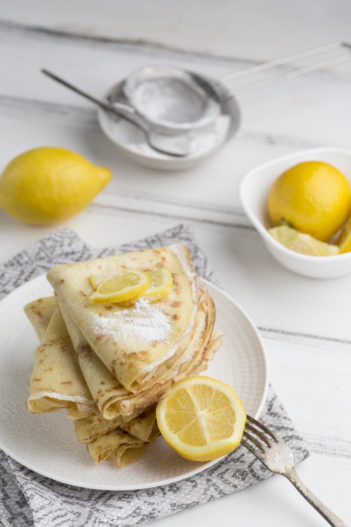 Fluffy lemon ricotta pancakes stacked high, drizzled with syrup